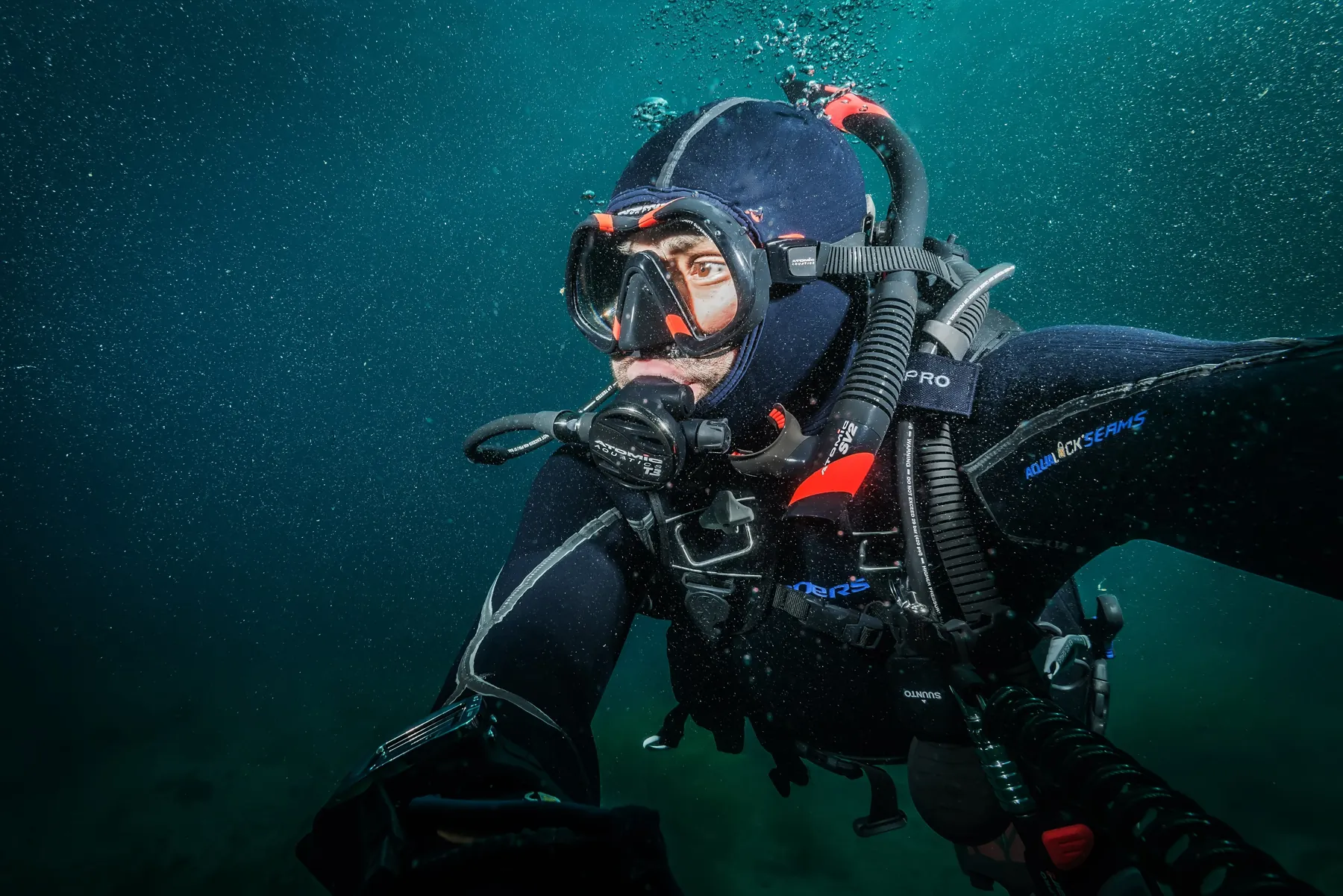 Javier Mendoza diving in full scuba gear in green Pacific water